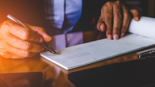 Une femme signe un chèque