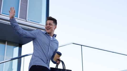 Un homme souriant fait un signe de main