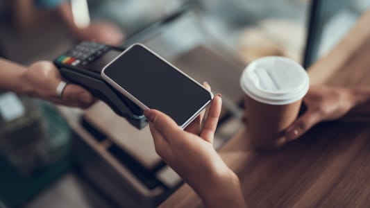 Une femme paye son café avec un smartphone