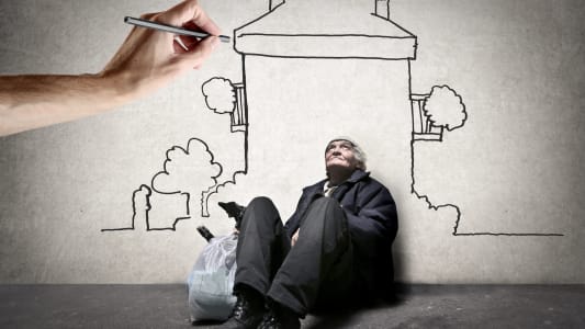 Une main dessine un logement au-dessus d'un sans-abri