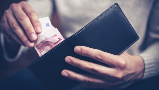 Un homme tirant un billet de 10 euros d'un portefeuille