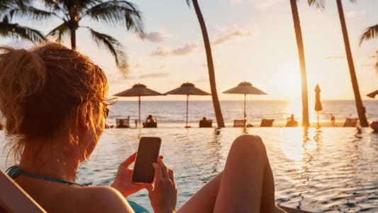 Une femme utilise son smartphone sur une plage