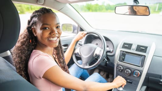 Une jeune conductrice dans sa voiture.