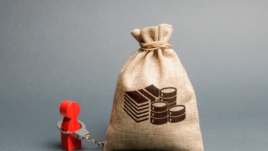 Un sac d'argent et une figurine menotte, symboles d'un surendettement ou d'un incident de paiement.