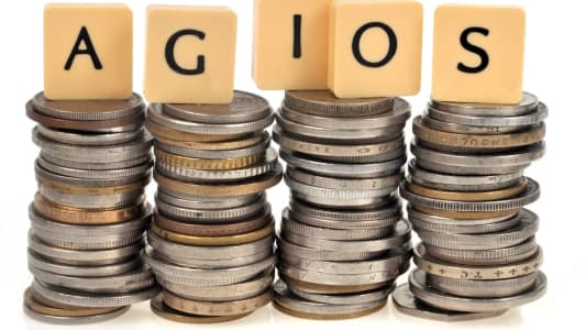 Des piles de pièces avec un panneau portant l'inscription Agios