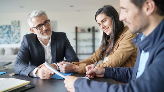 Un couple signe des documents face  un vendeur.