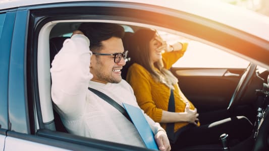 Deux jeunes ayant l'air effrays dans une voiture.