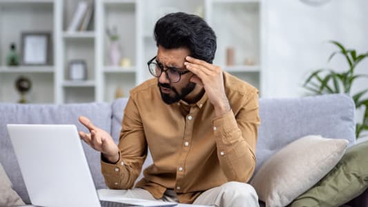 Un jeune devant son ordinateur l'air inquiet.