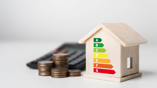 Une calculatrice et une maison portant les différentes étiquettes du DPE