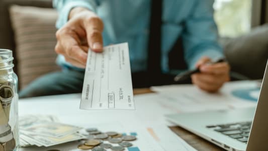 Un homme tend un chque.