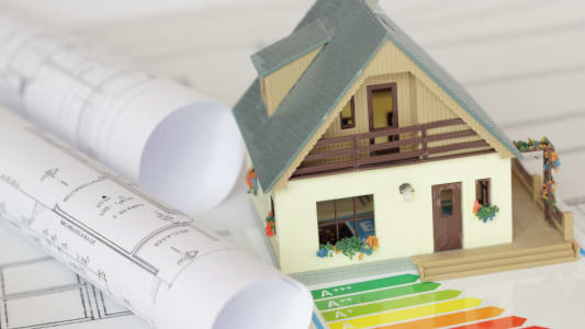 Une maison miniature avec des documents, notamment un DPE.