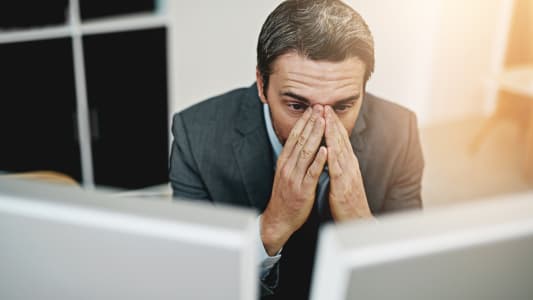 Un homme regarde deux crans avec inquitude.