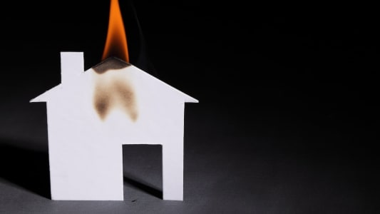 Une maison en papier qui prend feu.