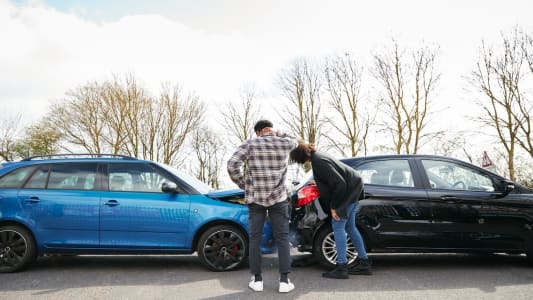 Deux automobilistes regardent deux voitures accident�es.