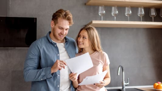 Un homme et une femme regardent un document l'air heureux.