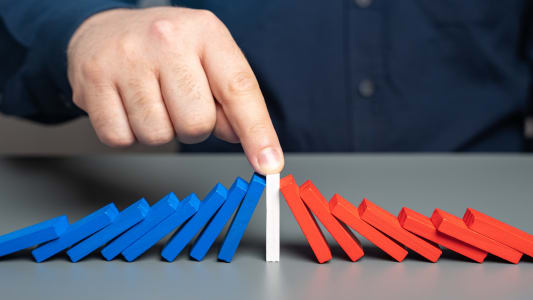 des dominos bleu et rouge tombent de chaque ct d'un domino blanc au centre.