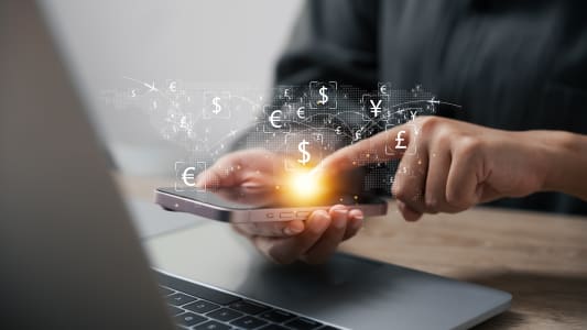 Un ordinateur et un tlphone sur lesquels s'affichent des euros des dollars et d'autres monnaies