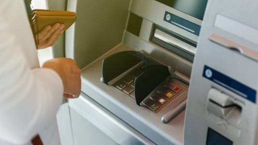 Une femme  un distributeur de billets.