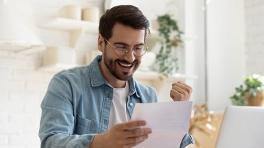 Un homme sourit en lisant un document.