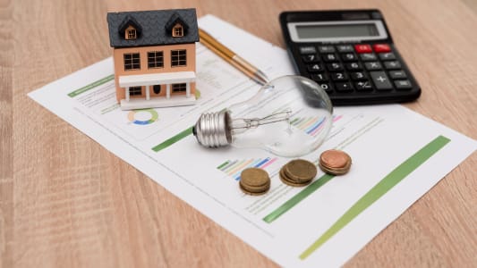 Une maison miniature, une ampoule et une facture.