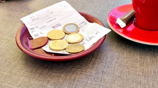 Des pices de monnaie et un billet laiss  ct d'une tasse  caf et d'un ticket de caisse.
