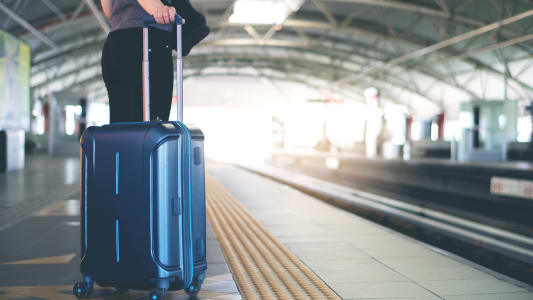 Quelqu'un tient une valise dans une gare.