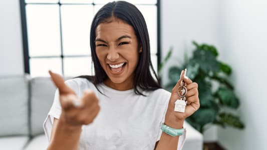 Une femme tient un porte clef en forme de maison dans sa main.