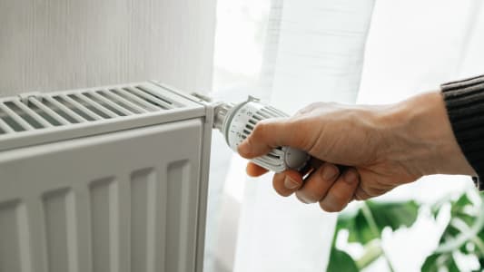 Quelqu'un tourne le thermostat d'un radiateur.