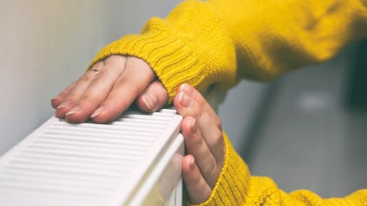Une personne met ses mains sur un radiateur.