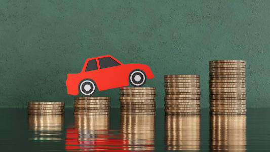 Une voiture miniature qui grimpe sur des piles de pices de monnaie.
