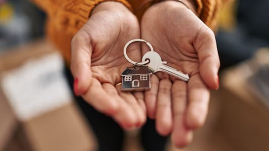 Quelqu'un tient dans ses mains un porte-clef en forme de maison.