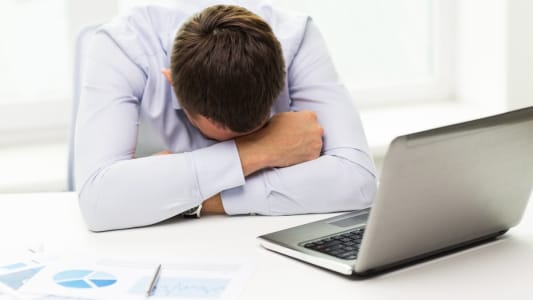 Un homme se prend la tte dans les mains devant son ordinateur.