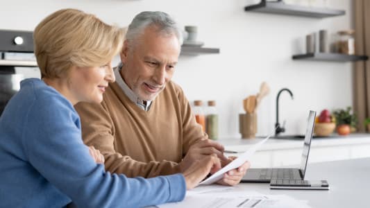 Deux personnes regardent des documents dans leur cuisine.