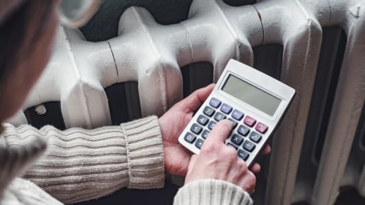 Quelqu'un tient une calculatrice à côté d'un radiateur.