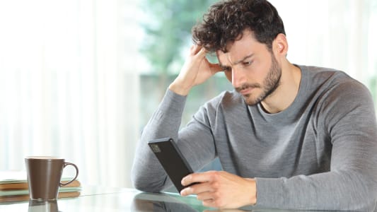 Un homme l'air inquiet regarde son tlphone.