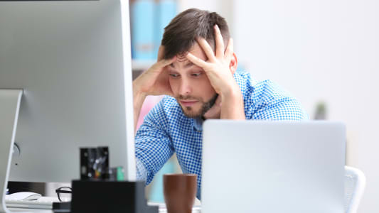 Un homme l'air inquiet devant son ordinateur.