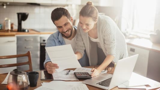 Un homme et une femme regarde un document l'air heureux.