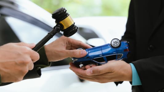 Un marteau symbole de la justice et une voiture miniature retourne.