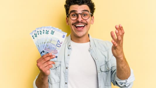 Un jeune homme tient plusieurs billets de 20 euros l'air content.