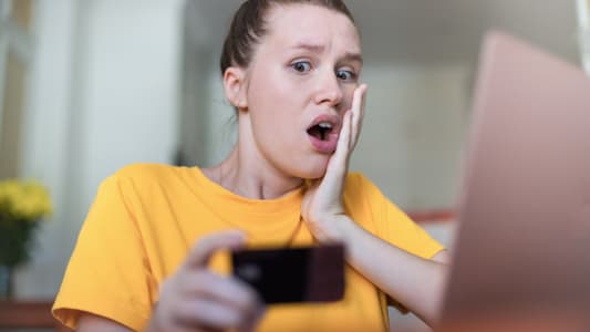 Une femme regarde une carte bancaire l'air effray.