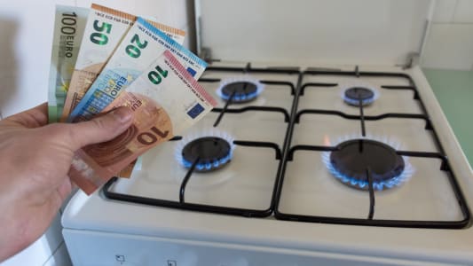 Quelqu'un tient des billets  ct d'une gazinire.