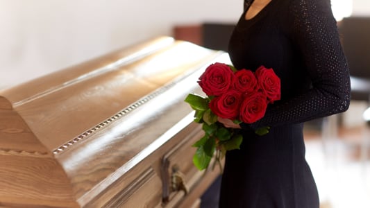 Une femme devant un cercueil.