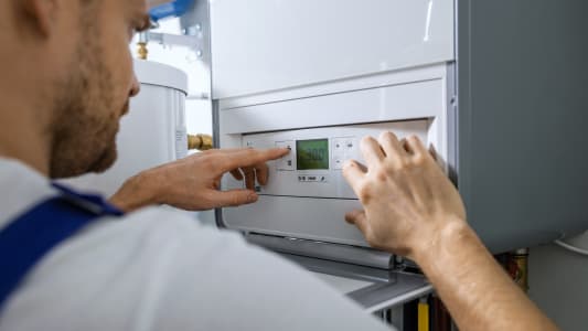 Un homme programme une chaudire gaz.