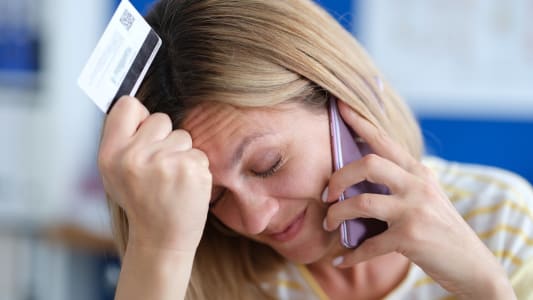 Une femme au tlphone tient sa carte bancaire.