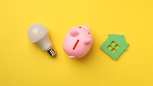 Une tirelire, une ampoule et le symbole d'une maison.