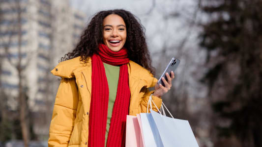 Une femme avec des sacs tient un téléphone.