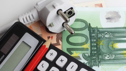 Une prise lectrique, un billet et une calculatrice.