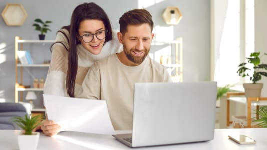 Un couple regarde son ordinateur l'air content.