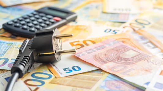 Des billets une calculatrice et une prise lectrique.