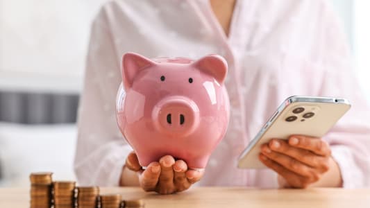 Une tirelire dans laquelle une personne met de l'argent.